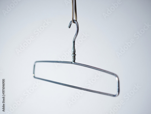 Modern steel clothing hanger with a slender, rectangular frame, hanging poised in an uncluttered minimalist environment, ready for efficient garment organization and style display