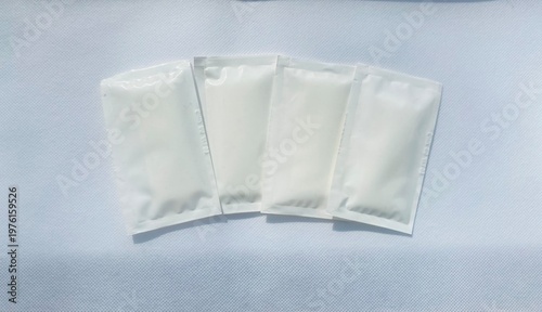 Minimal white wet wipe sachets on textured background, hygiene and personal care concept