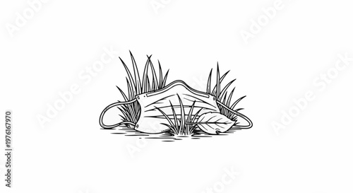 A discarded face mask rests amidst blades of grass