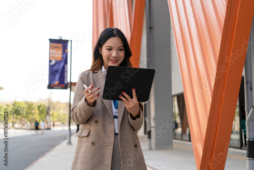 Asian businesswoman working on digital tablet with stylus outside modern building
