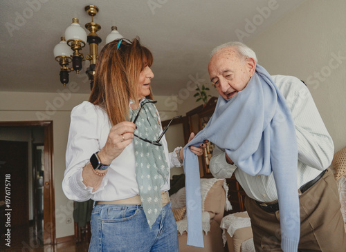 Tableau sur toile Daughter helping senior father with scarf at home