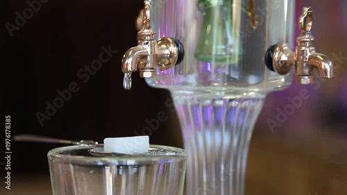 Hand closing absinthe fountain during traditional preparation ritual