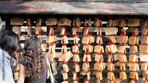 People at Japanese Shrine Displaying Wooden Ema Prayer Wish Tablets with Red Tassels