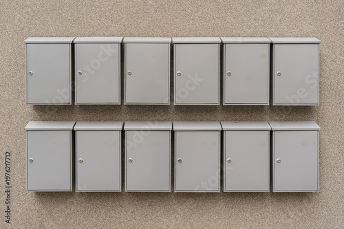 Wallpaper Mural Row Metal Mailboxes On Beige Wall, Twotier Arrangement Outside Apartment Building, Rectangular Doors With Locks And Small Handles, Textured Stucco Surface, Soft Neutral Lighting, Building Manager Torontodigital.ca