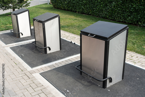 Wallpaper Mural Stainless Steel Charging Cabinets On Sidewalk, Serving Commuters With Compact Public Power Access Beside Paved Parking Bay, Visible Cables And Curb Protection, Trimmed Hedge Backdrop And Clean Modern Torontodigital.ca