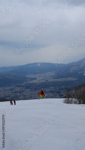 Snowboarder jumps mid-air over snowy mountain valley landscape, action sport