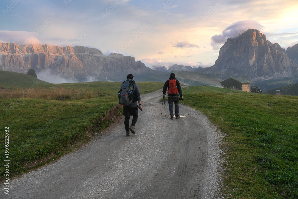 Fototapeta premium Tourists at sunset, with the Sella and Langkofel mountain ranges in the background. The Dolomites. Italy.