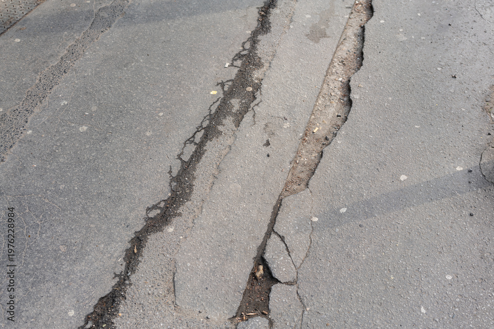 custom made wallpaper toronto digitalCracked Asphalt Pavement With Deep Fissures And Small Gravel Debris, Faded Markings And Uneven Surface, Overcast Urban Street Context, Visual Focus On Texture And Decay, Hazard For Vehicles