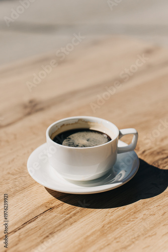 Cup of black coffee on a wooden table in a street cafe. Selective focus.