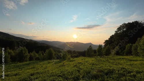Amazing warm sunset in beautiful mountains at early summer time. Big woods, cloudy sky in great wild nature. Outdoor travel destination concept