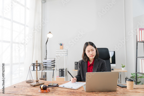 Legal Professional in Office: A focused legal professional diligently reviews documents at her desk, symbolizing the intricacies of the legal profession. 