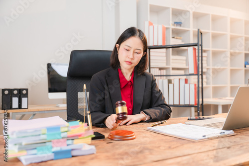 Foto Justice in Focus: A determined individual in a formal suit, wielding a gavel at a desk strewn with legal documents