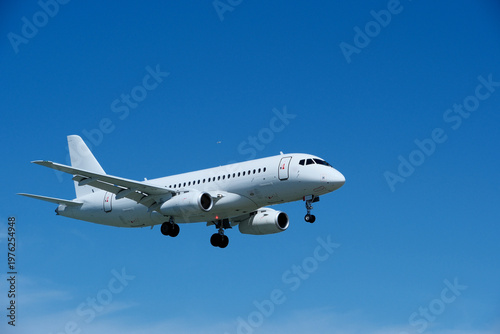 Commercial White Jet on Final Approach, Blue Sky with Light Clouds, Copy Space.