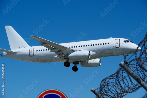 Commercial White Jet on Final Approach, Blue Sky with Light Clouds, Copy Space.