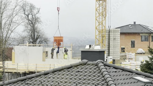 concrete hanging from crane at family home construction site