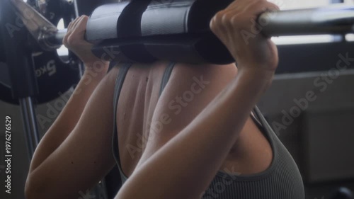 Close up of Caucasian woman with ponytail squatting in smith machine during lower body workout in gym