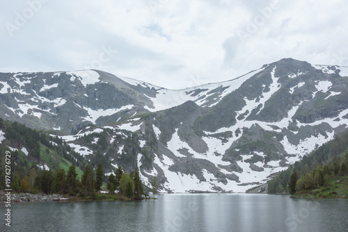 Mountain lake in rainy weather. Alpine lake between green hills with conifer ...