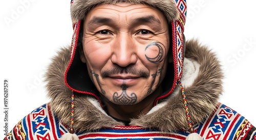 A close-up portrait of an indigenous man wearing a fur-lined hood, adorned with facial tattoos. The warm light highlights skin texture