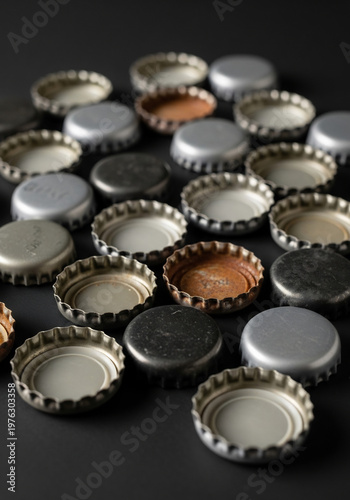 黒背景に並んだ使用済み金属製の王冠キャップの俯瞰写真