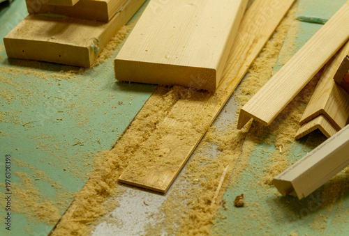 Fotografie The image shows a woodworking workshop scene with raw lumber pieces scattered on a workbench covered in sawdust, showcasing the process of constructing a mortise and tenon joint