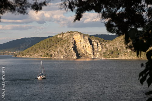 panorámica de un lago con un velero y una montaña al fondo en el pantano de Entrepeñas, Guadalajara, España.