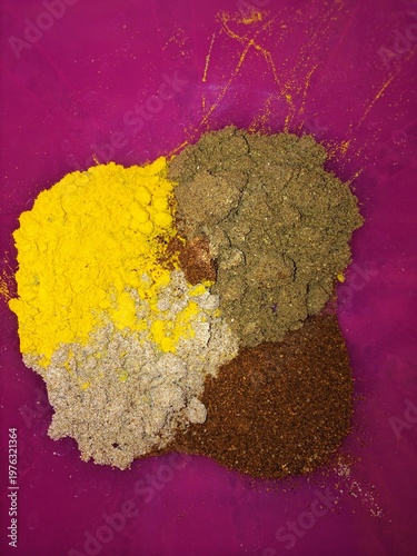 Gewürzhäufchen auf einer rosa Unterlage.
