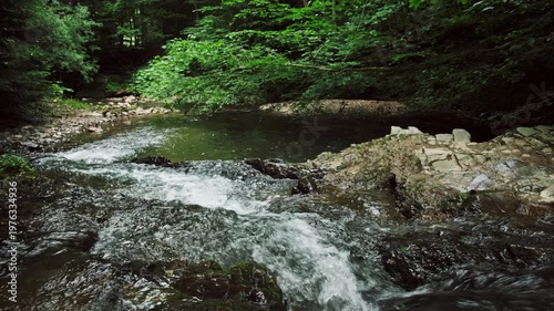 Mountain river water with stone rapids and splashes at summer time. Background of fresh water with fast rapids in wild river. Natural wonder, quiet place for green tourism concept