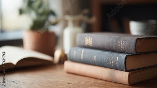 Stack of three books on a wooden table. the books are of different sizes and colors - one is black, one is brown, and one is white.