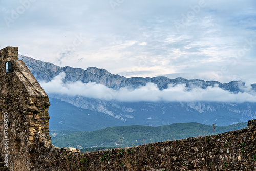 Ainsa Castle in the medieval village of Ainsa in Spain surrounded by stone walls with an elevated path leading to it.