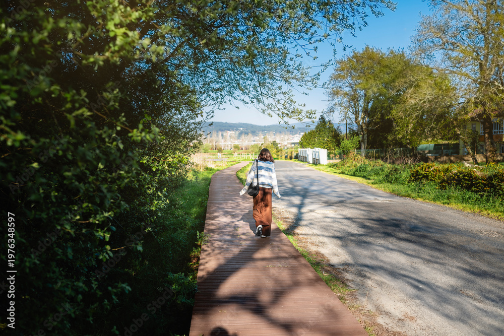 Obraz premium Woman walking on boardwalk path in tambre countryside