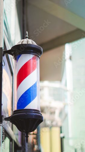 Foto Vintage barber pole with red, white, and blue stripes outside barbershop