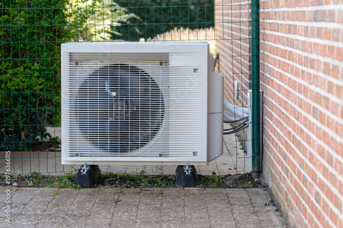 Konstfotografi Outdoor unit of a modern air source heat pump installed next to a brick wall of a residential house