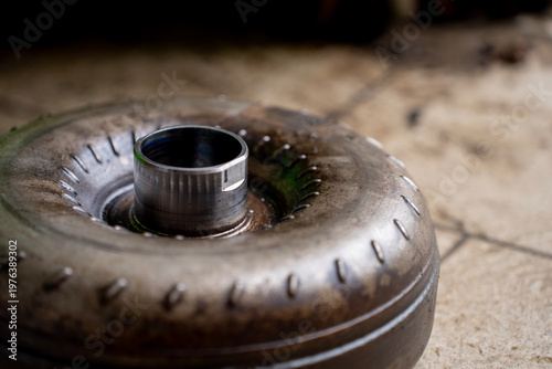 Slika na platnu Top view of a used torque converter from an automatic transmission placed on a workshop floor, showing metal housing and central hub
