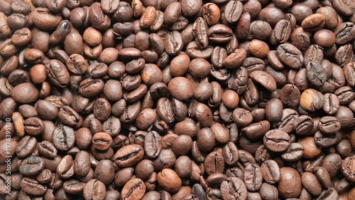 Top view close-up video of roasted coffee beans with a rotating motion creating a dynamic textured pattern. Rich brown tones and detailed surface highlight aroma, flavor and coffee culture