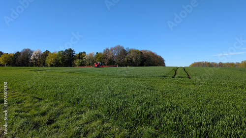 Agricultural tractor spreading manure on field in spring,  