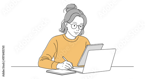 A focused young woman with glasses and a bun hairstyle is diligently working on her laptop while simultaneously writing notes in a physical notebook.