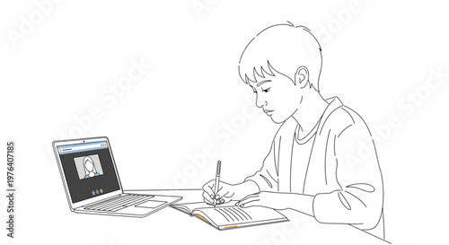 A focused young boy attentively studies at a desk, writing notes while participating in an online lesson on his laptop.