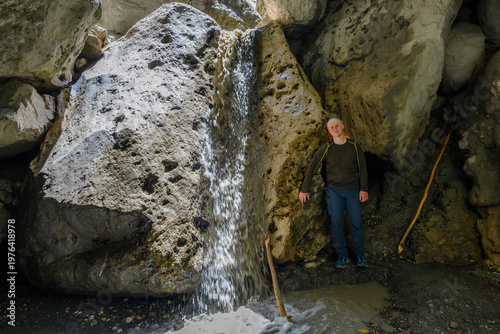 Man exploring a waterfall in a rock canyon cave. Dagestan Russia.