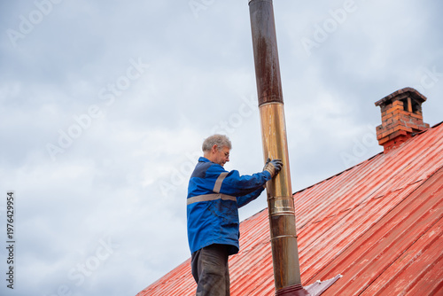 Slika na platnu Chimney sweep repairing steel vent pipe on house rooftop