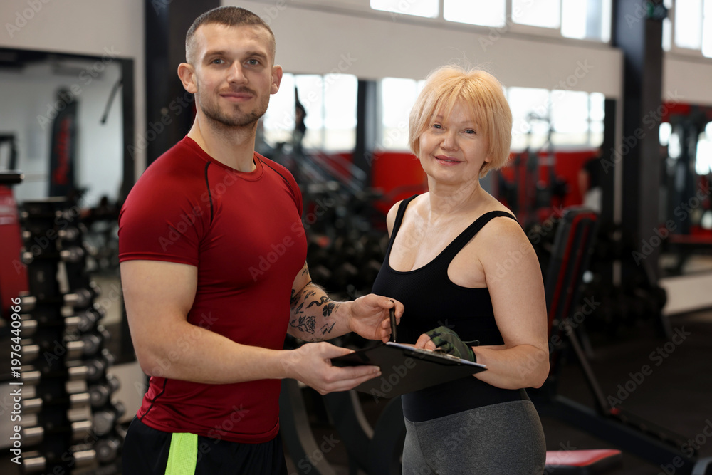 Fototapeta premium Senior woman with professional trainer in gym