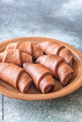 Fresh chocolate croissants on ceramic plate rustic bakery breakfast scene closeup composition