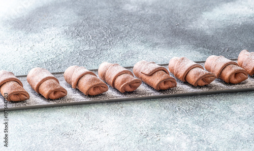 Chocolate croissants dusted with sugar on slate platter bakery top view composition