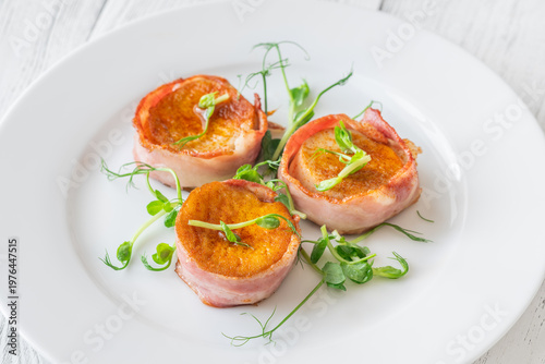 King oyster mushrooms wrapped in crispy bacon served as elegant gourmet appetizer on white plate