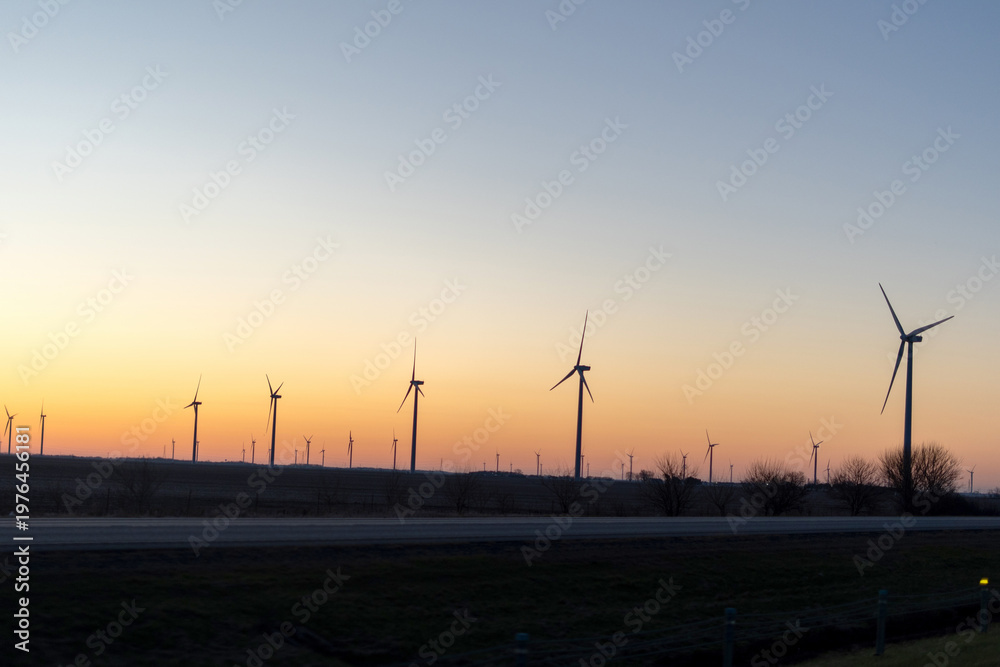 Fototapeta premium Wind turbines at sunset over rural landscape, renewable energy concept