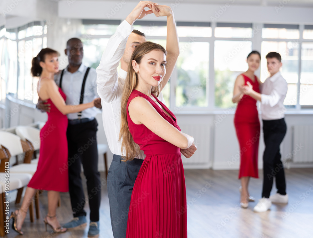 Fototapeta premium During rehearsal of reporting concert, young man and girl participants of dance workshop perform figure waltz. Group training and rehearsal, preparation for competitions