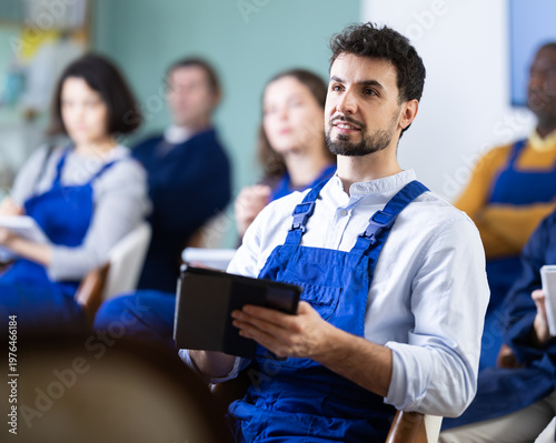 Fotografía Man in overalls takes notes in an electronic notebook during a refresher course