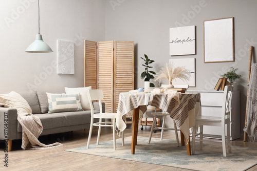 Interior of stylish dining room with table, sofa and folding screen