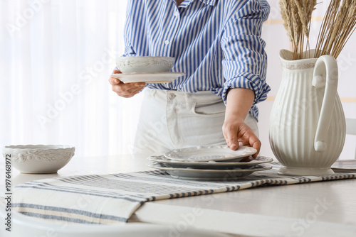 Young woman putting dishes ...