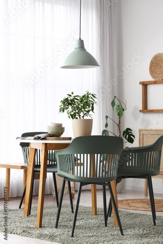 Interior of light dining room with table, lamp and window
