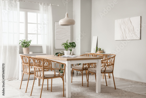 Interior of light dining room with table, plants and paintings